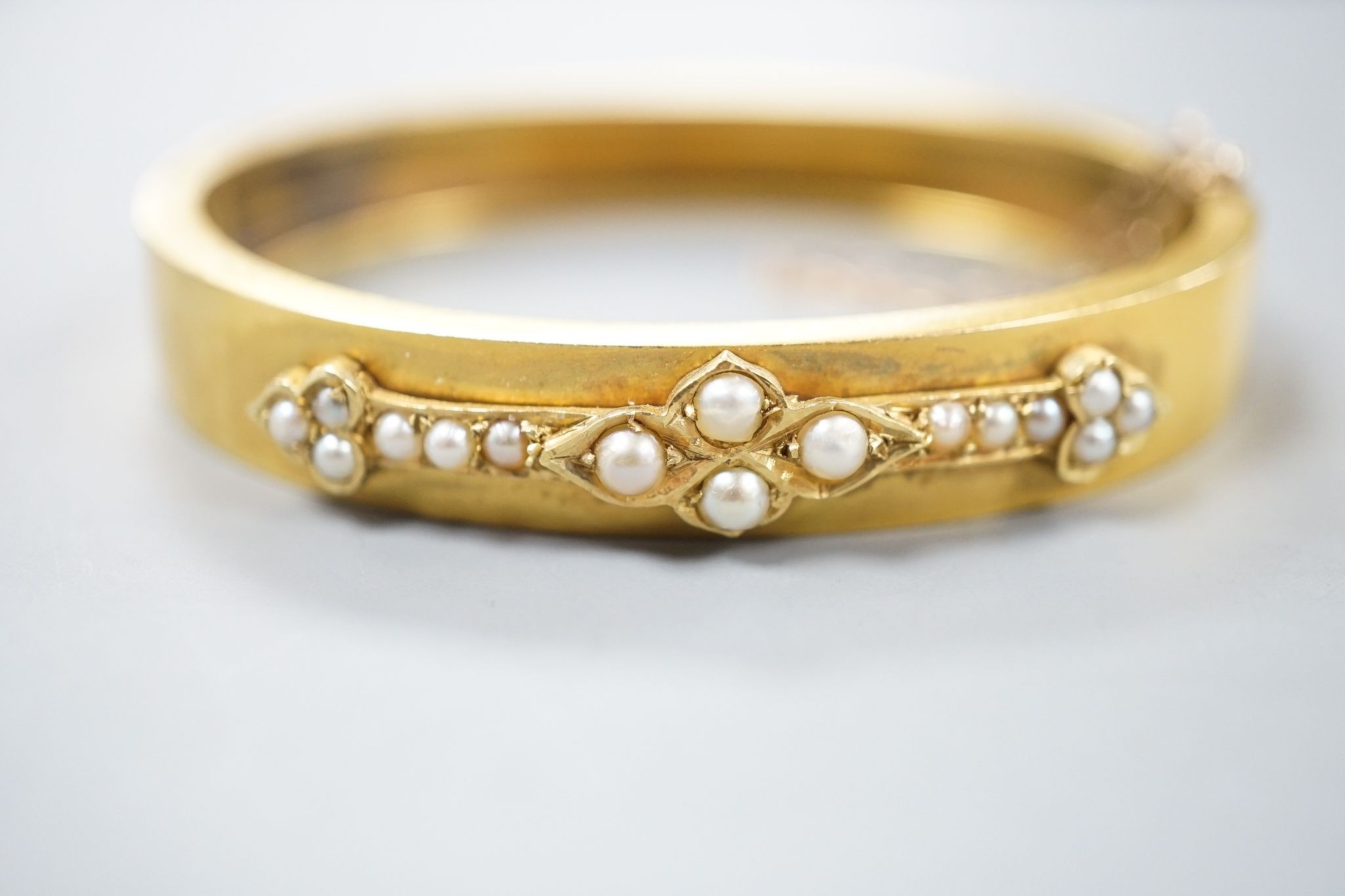 A Victorian yellow metal and split pearl set hinged bangle, interior diameter 55mm, gross weight 15.6 grams.